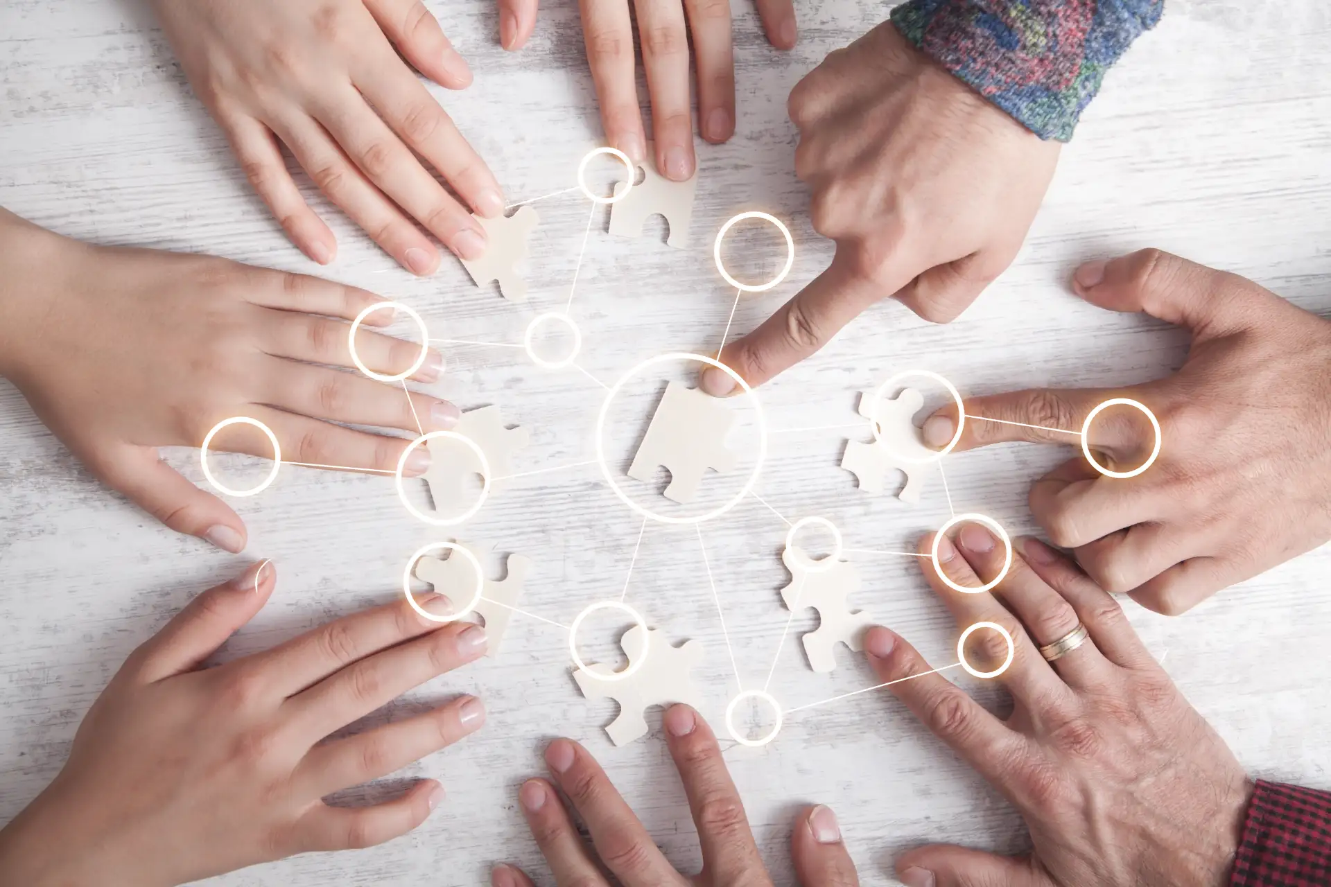 Mehrere Hände fügen gemeinsam Puzzleteile zusammen – Symbol für Teamarbeit, Inklusion und Vernetzung in sozialen Einrichtungen